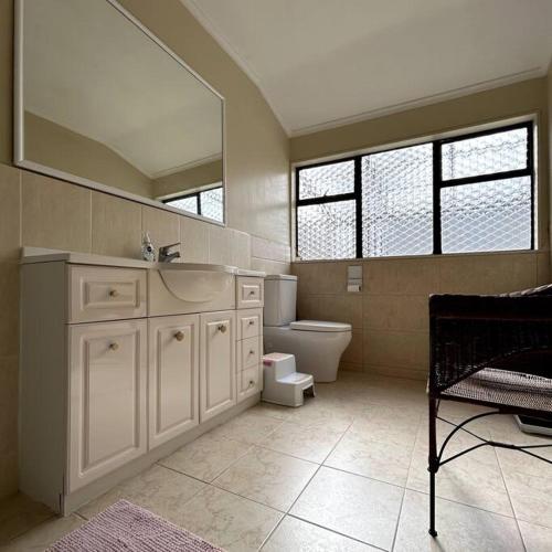 a bathroom with a sink and a toilet and a mirror at Peaceful Green Bay Charmer in Auckland