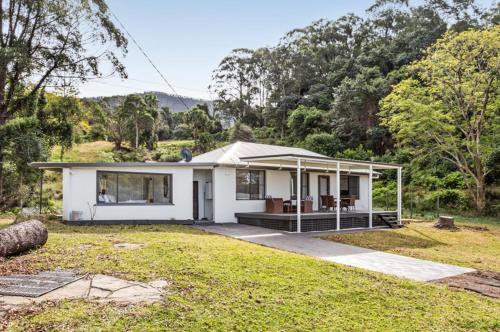a white house in the middle of a yard at Deer Valley Farm Stay Illawarra sleeps up to 9 in Kembla Grange