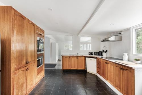a large kitchen with wooden cabinets and white counters at Deer Valley Farm Stay Illawarra sleeps up to 9 in Kembla Grange