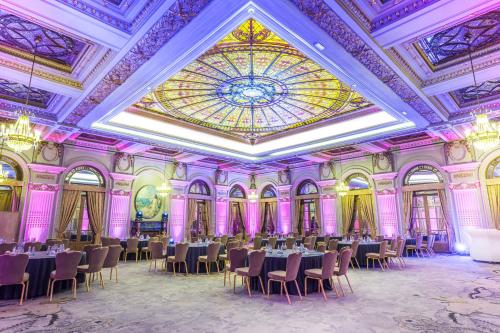 a ballroom with tables and chairs and a stained glass ceiling at InterContinental Athenee Palace Bucharest by IHG in Bucharest