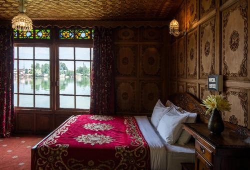 a bedroom with a bed with a red blanket and a window at Mascot Houseboats in Srinagar