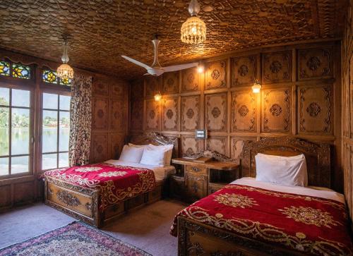 a bedroom with two beds and a table and a window at Mascot Houseboats in Srinagar