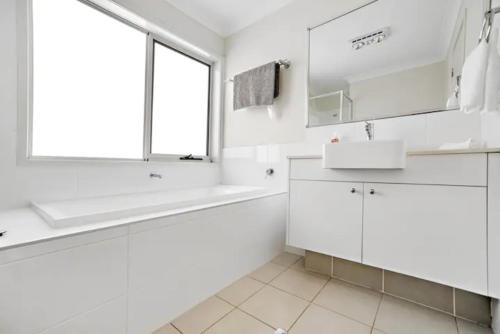 a white bathroom with a sink and a window at Kellyvile Delight 5BrHouseParkingShopping Center in Kellyville