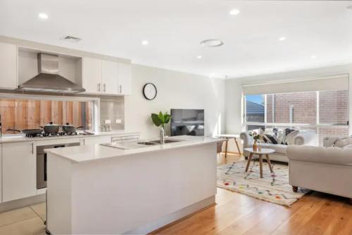 a kitchen and living room with white cabinets and a couch at Kellyvile Delight 5BrHouseParkingShopping Center in Kellyville