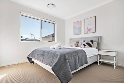 a white bedroom with a bed and a window at Kellyvile Delight 5BrHouseParkingShopping Center in Kellyville
