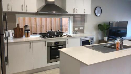 a kitchen with white cabinets and a stove top oven at Kellyvile Delight 5BrHouseParkingShopping Center in Kellyville
