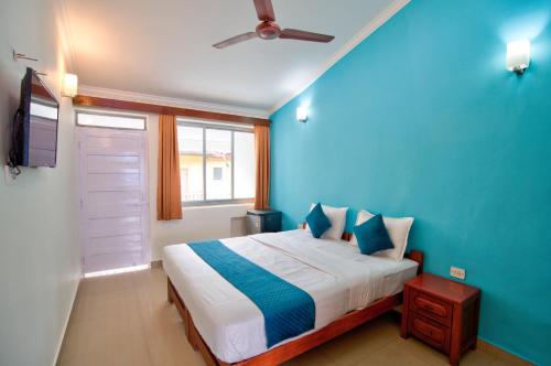 a blue bedroom with a bed and a ceiling fan at Candolim Beach Vaddo 15 in Calangute