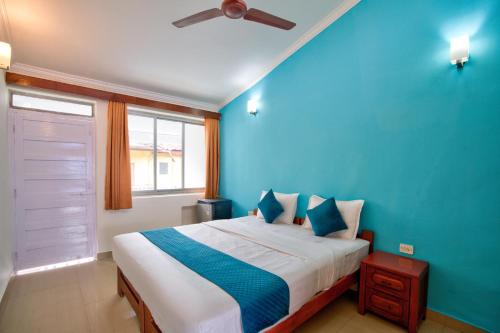 a bedroom with a bed with a blue wall at Candolim Beach Vaddo 15 in Calangute