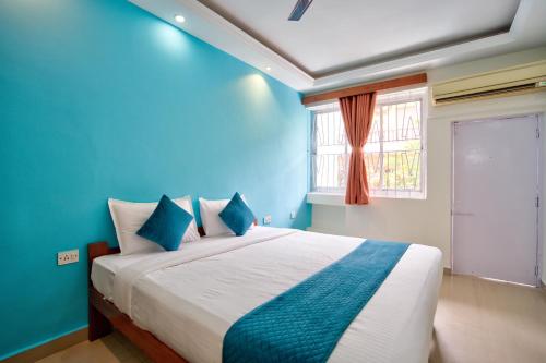 a bedroom with a bed with blue walls and a window at Candolim Beach Vaddo 15 in Calangute