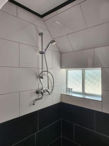 a shower in a tiled bathroom with a window at Ons kleine huisje in Gasselte