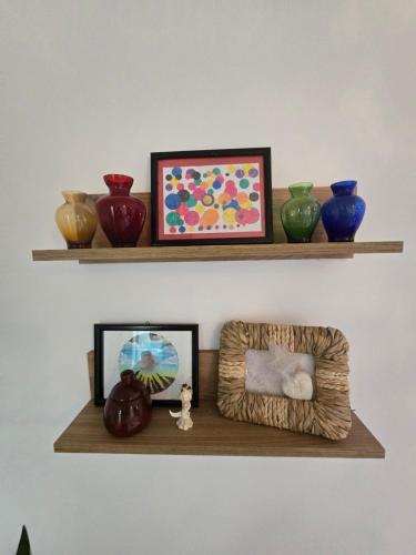 a shelf with different colored vases and a picture at Apartmani Krunet in Kruševac