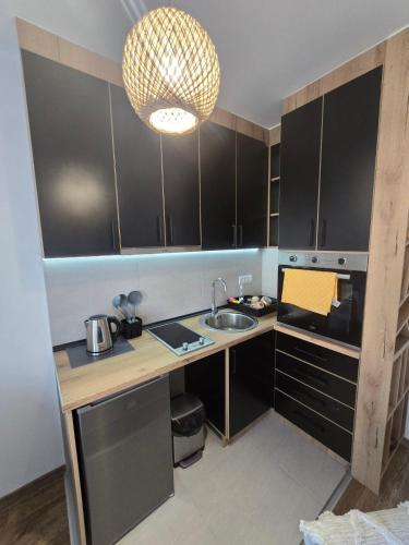 a kitchen with black cabinets and a sink and a light at Apartmani Krunet in Kruševac