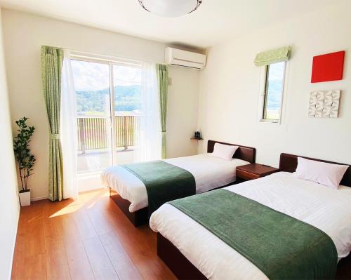 zwei Betten in einem Zimmer mit Fenster in der Unterkunft K Cottage in Fujikawaguchiko