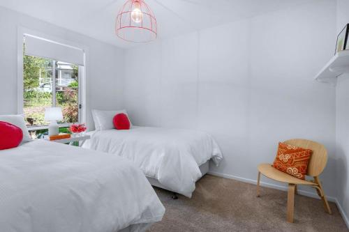 a bedroom with two beds and a chair and a window at Elmwood - By Berry Getaways in Berry