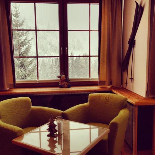 a living room with two chairs and a table and a window at Hotel Karl Schranz in Sankt Anton am Arlberg