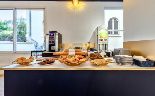 a counter with bread and pastries in bowls on it at Hotel Espadon bleu in Le Lavandou