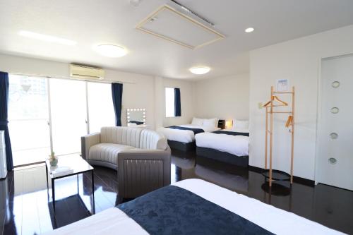 a hotel room with two beds and a couch at Ideal Yuuhigaoka イデアール夕陽丘 in Osaka