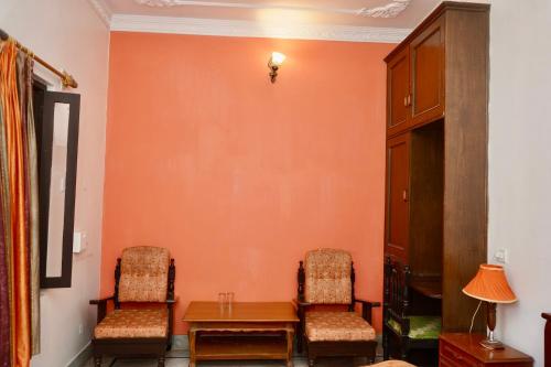 two chairs and a table in a room with orange walls at Haveli Katkoun in Būndi