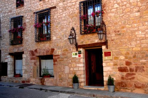 un bâtiment en pierre avec des fenêtres et des plantes en pot dans l'établissement Los Cuatro Caños, à Sigüenza