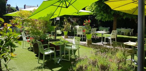 - un jardin avec des tables, des chaises et un parasol vert dans l'établissement Hotel Le Lion d'Or, à Saint-Geniez-dʼOlt