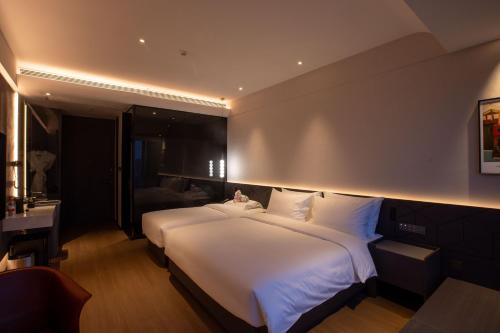 a bedroom with a large white bed and a desk at Maison New Century Hotel Cixi Hangzhou Bay in Cixi