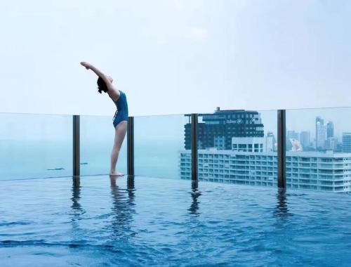 una mujer parada en el borde de una piscina en Central Pattaya, Sky Pool and Amazing Location, en Pattaya central