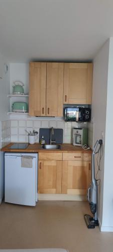 une cuisine avec des armoires en bois et un réfrigérateur blanc dans l'établissement Cabourg Plage, à Cabourg