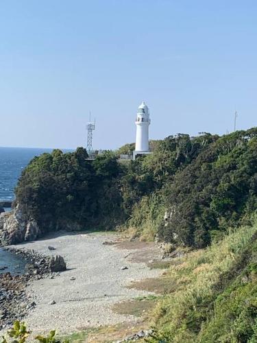 a lighthouse sitting on top of a hill next to the ocean at 紀州安兵衛 in Kushimoto