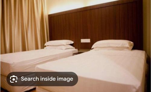 two beds in a hotel room with an image at Reggae Inn in Bintulu