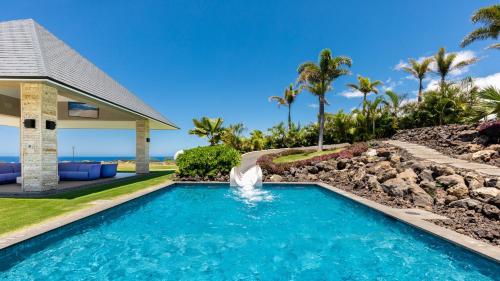 a swimming pool with a waterfall in front of a house at ❤PiH❤ BLUE TRANQUILITY Heated Private Pool Spa Detached Ohana Suite in Waimea