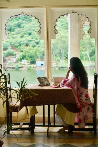 a woman sitting at a table with a laptop at Haveli Katkoun in Būndi