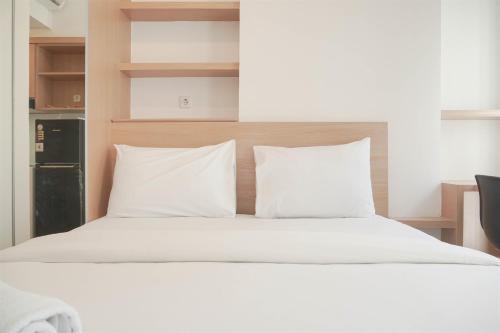 a bed with white sheets and pillows in a room at Simply and Cozy Studio at Tokyo Riverside PIK 2 Apartment By Travelio in Rawalembang