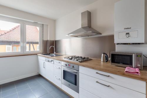 une cuisine avec des armoires blanches et un four à plaques de cuisson dans l'établissement le schwendi, à Colmar