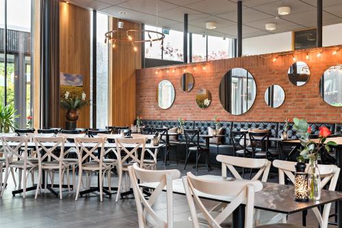 a restaurant with tables and chairs and mirrors at Best Western Valhall Park Hotell in Ängelholm