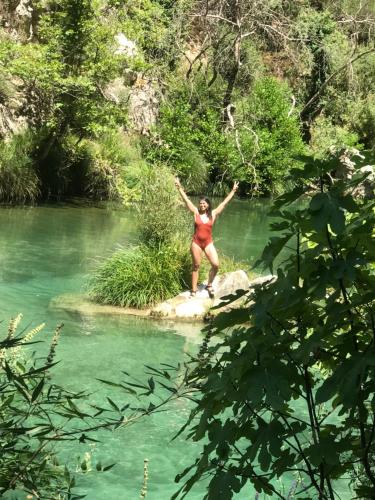 a woman standing on a rock in a river at Gourgiana Apartments in Andritsaina
