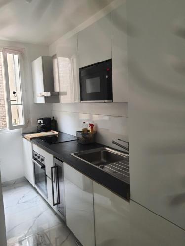 a white kitchen with a sink and a microwave at suresnes centre in Suresnes