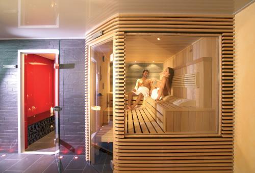 a couple sitting on a deck in a room at Hotel Rovanada Wellness & BergNatur in Vals