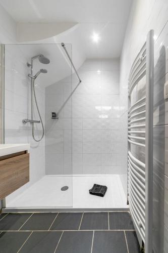 une salle de bain blanche avec une douche et un lavabo dans l'établissement Le Vizier - Appartement design avec parking en centre ville, à Vichy