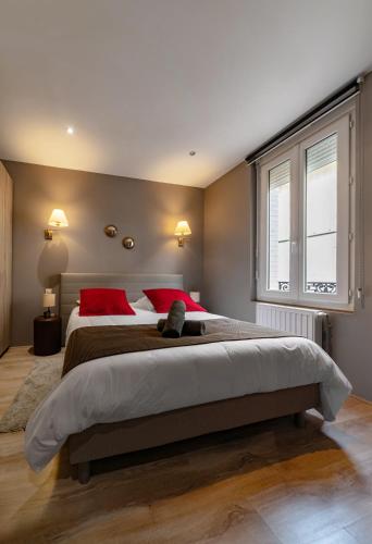 Cette chambre comprend un grand lit avec des oreillers rouges et une fenêtre. dans l'établissement Le Vizier - Appartement design avec parking en centre ville, à Vichy