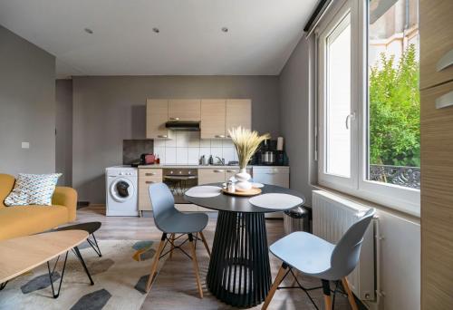 une cuisine et un salon avec une table et des chaises dans l'établissement Le Vizier - Appartement design avec parking en centre ville, à Vichy