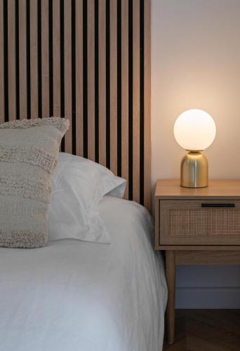 a bed with a wooden headboard and a lamp on a night stand at Résidence Serbie - Appartements design et climatisés en centre ville in Vichy