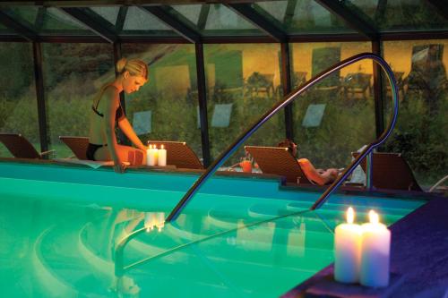 a woman sitting in a swimming pool with candles at Hotel Rovanada Wellness & BergNatur in Vals