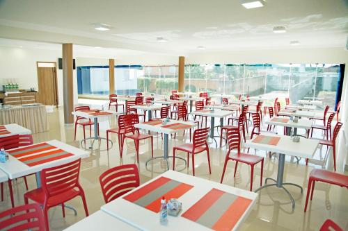 ItuiutabaにあるBernal Hotel Econômicoのテーブルと赤い椅子が並ぶ部屋