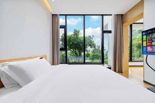 a white bed in a room with a large window at XMAN Sunrise Peaks Resort--Free Pick-up in Zhangjiajie