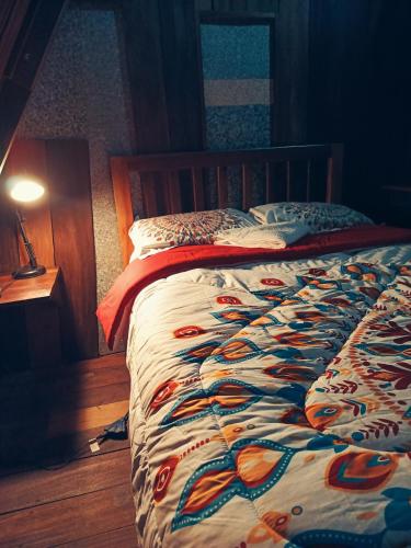 a bed with a colorful comforter on it in a bedroom at Cabaña 79 Papallacta Alpina in Papallacta