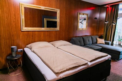 a bed in a room with a couch and a mirror at Motel1- A megfizethető luxus! in Dunaújváros