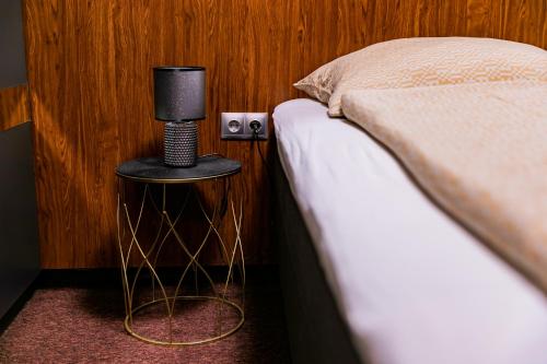 a bedroom with a bed and a night stand with a lamp at Motel1- A megfizethető luxus! in Dunaújváros