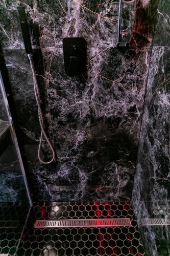 a bathroom with a black marble shower with a hose at Motel1- A megfizethető luxus! in Dunaújváros