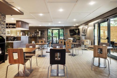 un restaurant avec des tables et des chaises dans une cafétéria dans l'établissement Campanile Béthune - Fouquières-Les-Béthune, à Fouquières-lès-Béthune