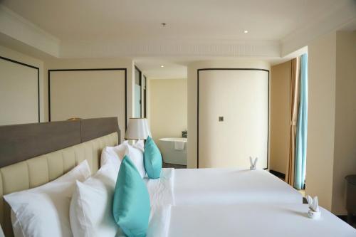 a bedroom with a large white bed with blue pillows at Charmant Suites a Boutique Hotel Can Tho in Can Tho